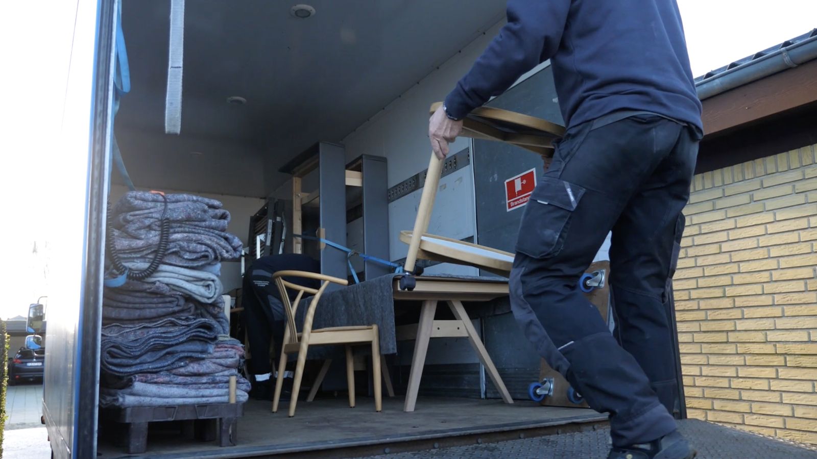 Flyttemand læsser stole og et bord ind i en flyttebil